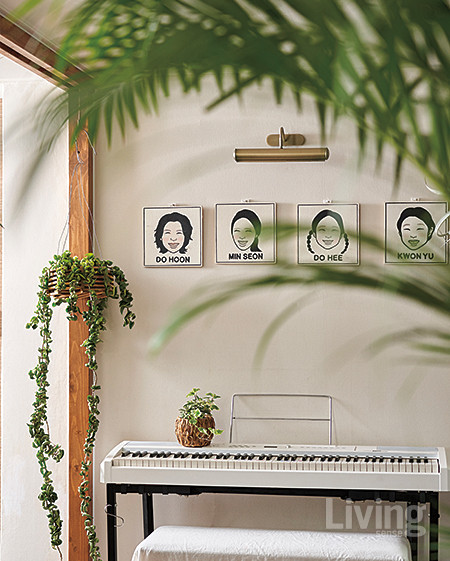 피아노 위 허전한 벽면에 가족 얼굴을 일러스트로 그린 액자를 걸고 옆에 다육식물인 호야 콤팩타 행잉 플랜트를 배치했다. 